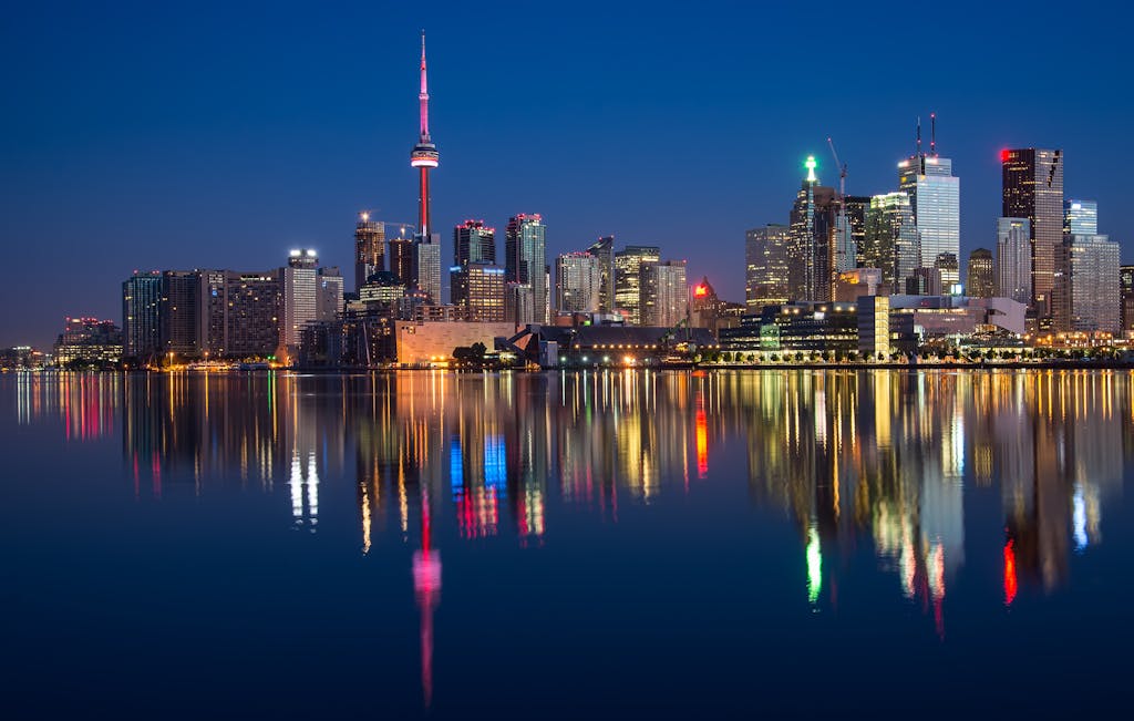Stunning night view of Toronto skyline reflecting on water with CN Tower prominent.
